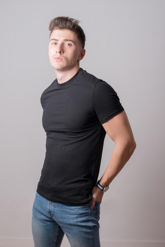 jonge man gekleed met een zwart t-shirt en jeans. grijze achtergrond. foto