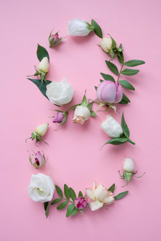 figuur 8 gemaakt van verschillende bloemen op roze achtergrond foto