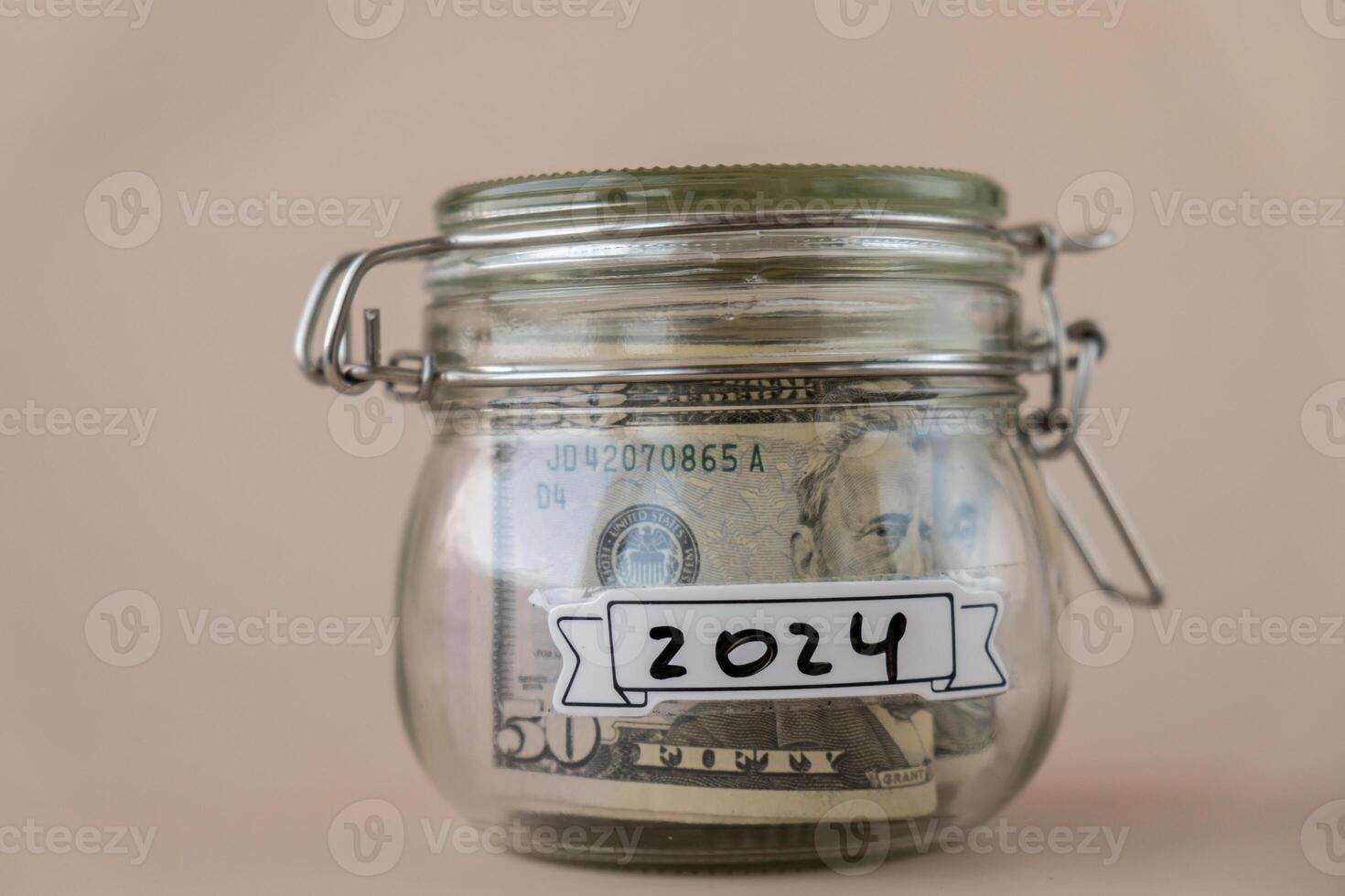 besparing geld in glas pot gevulde met dollars bankbiljetten. 2024 jaar transcriptie in voorkant van kan. beheren persoonlijk financiën extra inkomen voor toekomst onzekerheid. beige achtergrond foto