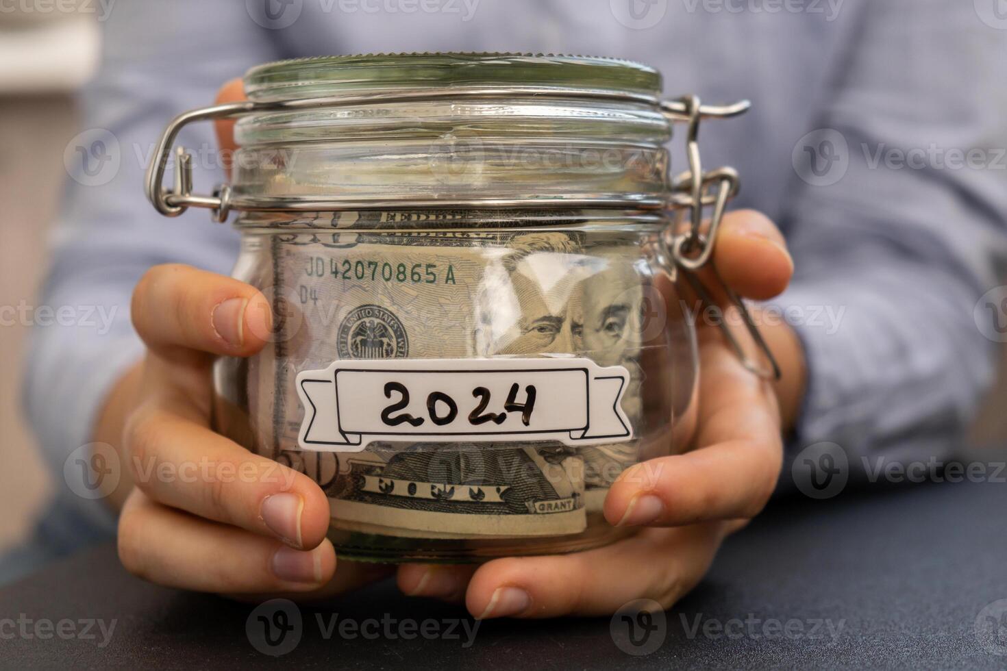 vrouw handen Holding glas pot vol van Amerikaans valuta dollars contant geld bankbiljet met tekst 2024. voorbereiding besparing geld. matig consumptie en economie. verzamelen geld foto