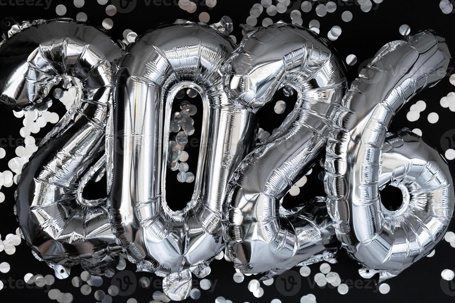 gelukkig nieuw jaar 2026 metalen ballonnen met confetti Aan donker zwart achtergrond. groet kaart zilver folie ballonnen getallen Kerstmis vakantie concept. viering partij felicitatie decoratie foto