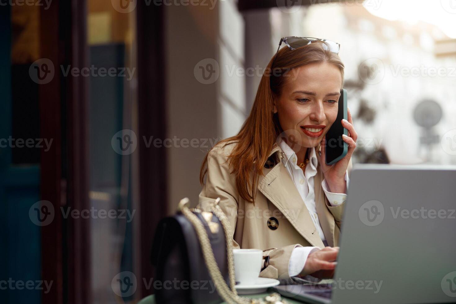 glimlachen Europese zakenvrouw pratend telefoon terwijl werken online zittend Bij buitenshuis cafe terras foto