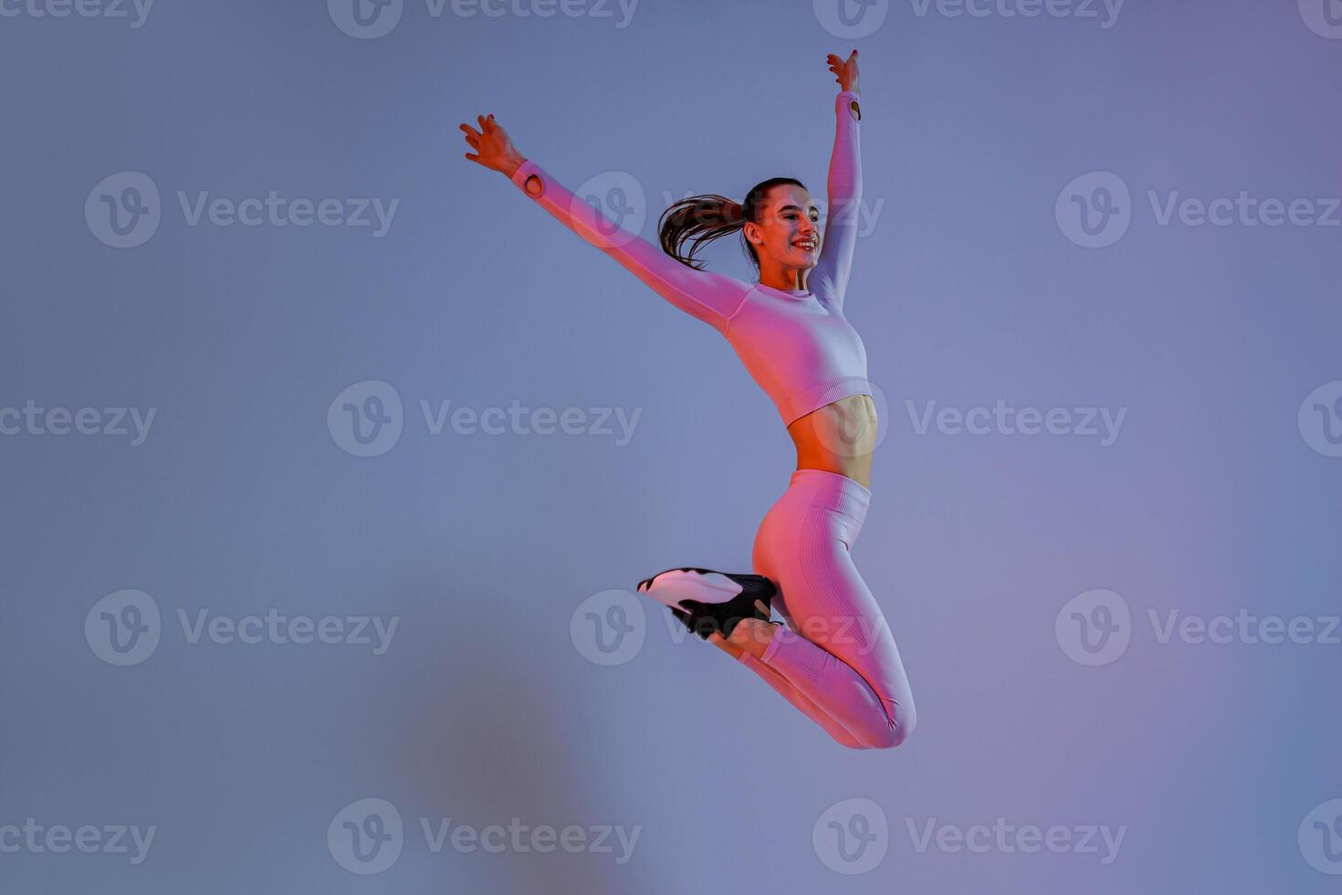 glimlachen sportief vrouw in sportkleding jumping Aan studio achtergrond. sport en gezond levensstijl foto