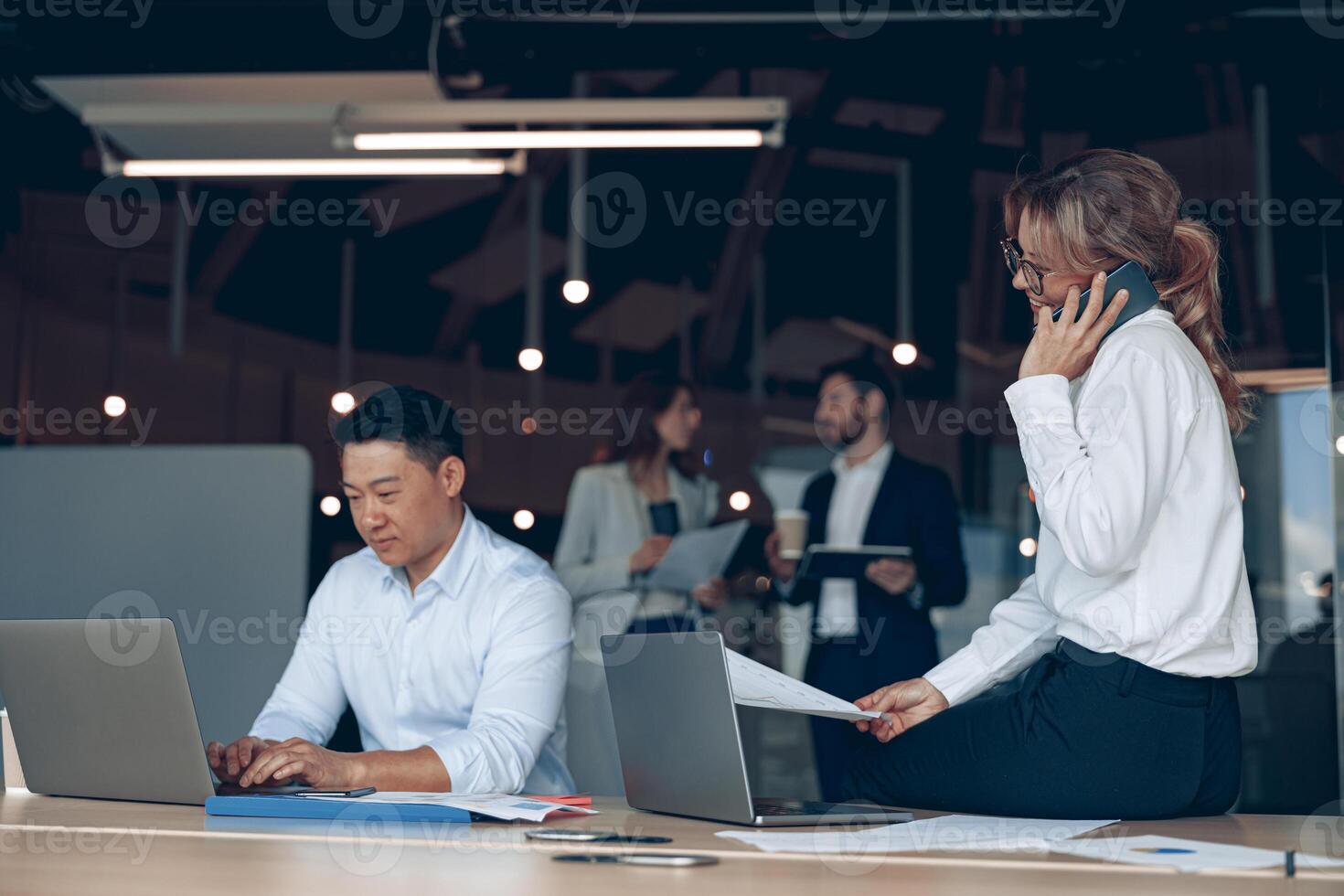 volwassen bedrijf vrouw zittend Aan tafel en pratend telefoon naar oplossen probleem in modern kantoor foto