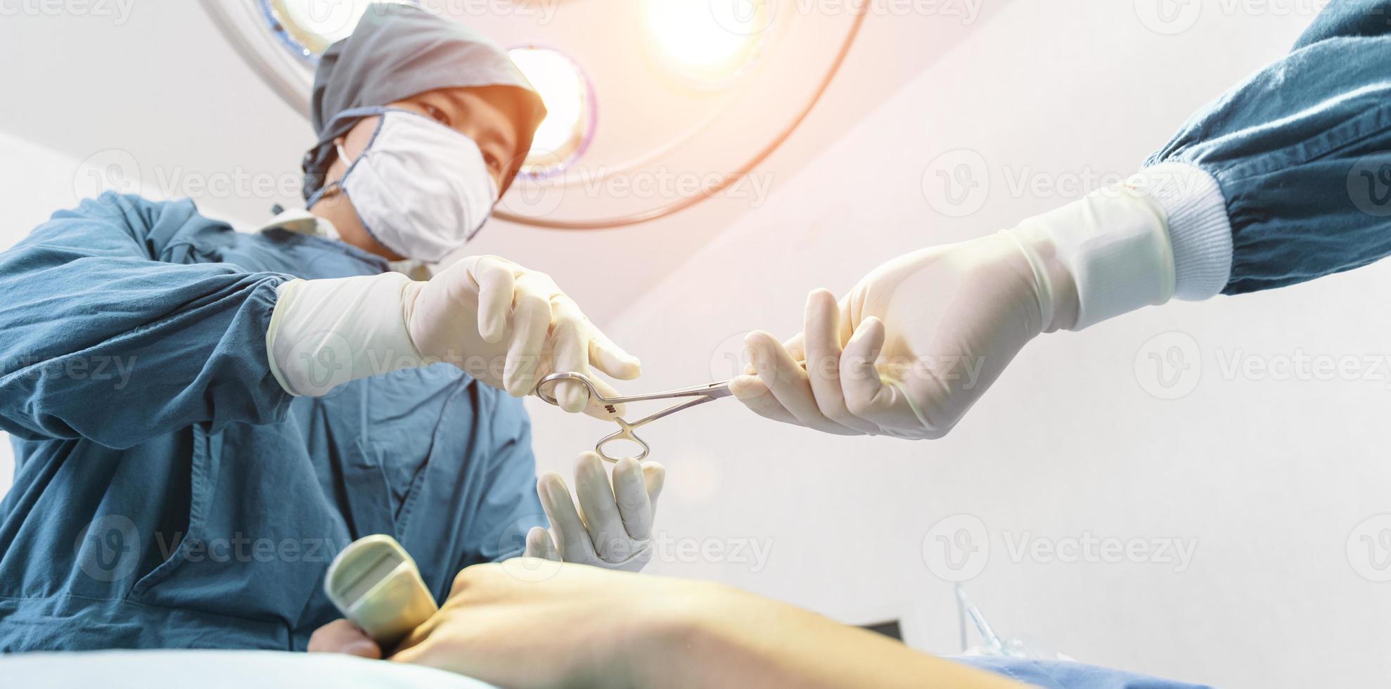 assistent deelt instrumenten uit aan chirurgen tijdens operatie. chirurgie en noodconcept foto