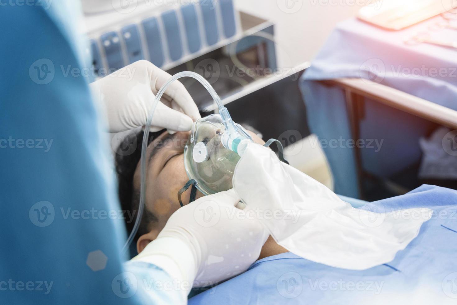 assistent-chirurg zette de patiënt op een beademingszuurstofmasker ter voorbereiding op de operatie. foto