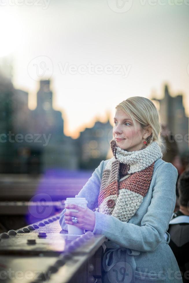 vrouw op de brooklyn bridge kijken naar manhattan met een kopje koffie foto