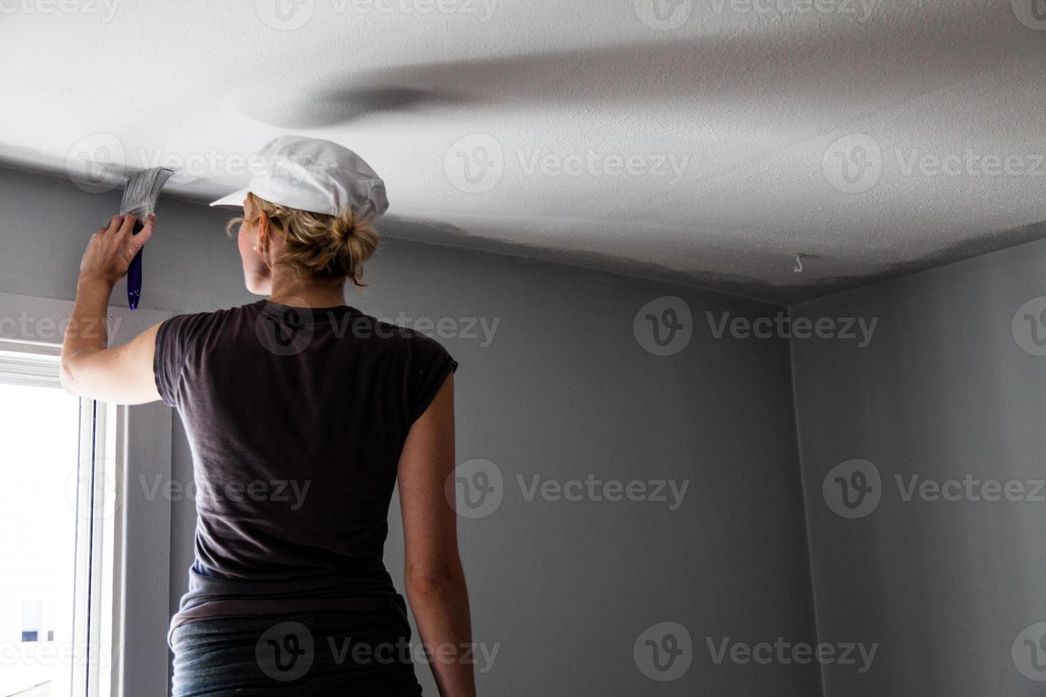 vrouw die de randen van het plafond schildert foto