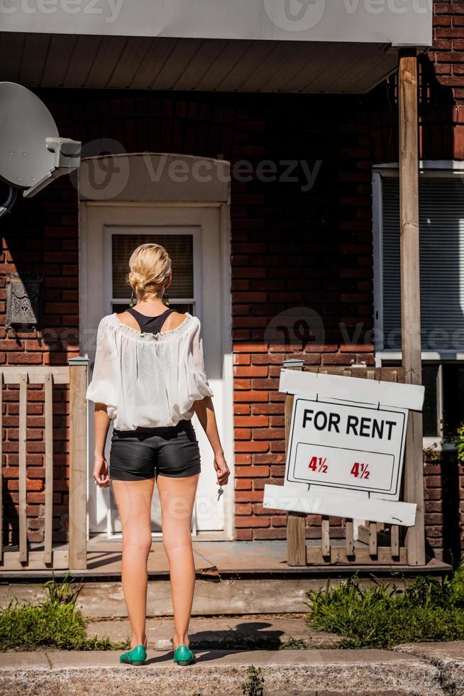 jonge vrouw die voor haar nieuwe appartement staat foto