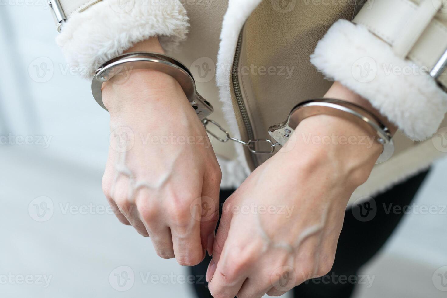 een vrouw wie heeft geweest gearresteerd en heeft haar handen geboeid achter haar terug naar de achterkant. de gevangene is in afwachting vervoer naar de gevangenis. foto