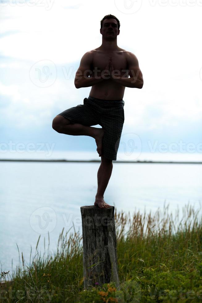 man silhouet doet yoga op een boomstronk in de natuur foto