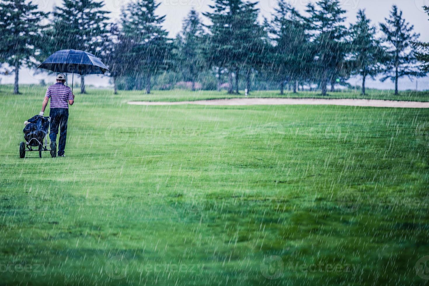 golfer op een regenachtige dag die de golfbaan verlaat foto