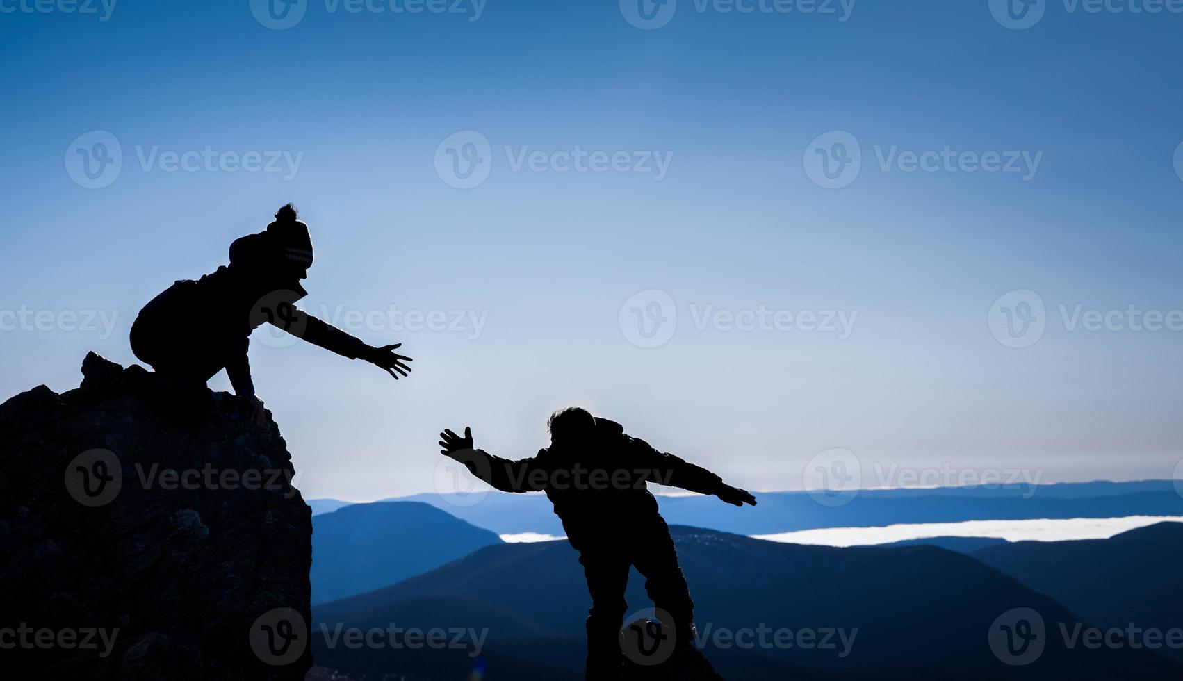 paar in silhouetten die elkaar helpen voor succes foto