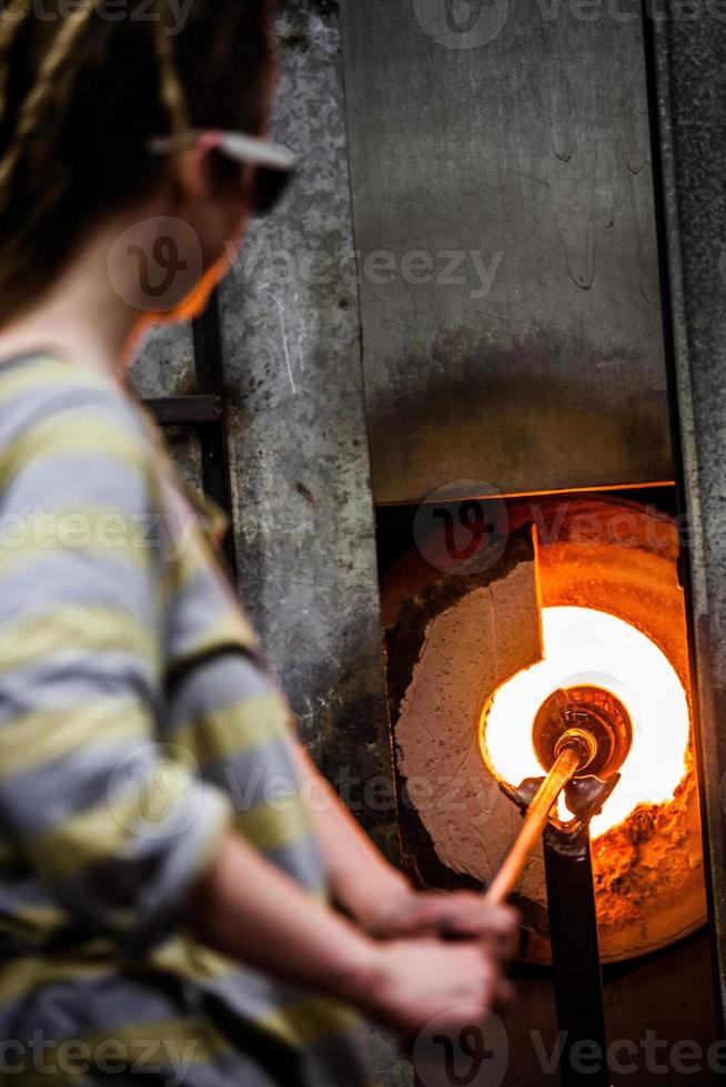 glasmaker knipperend stuk glas in de oven foto