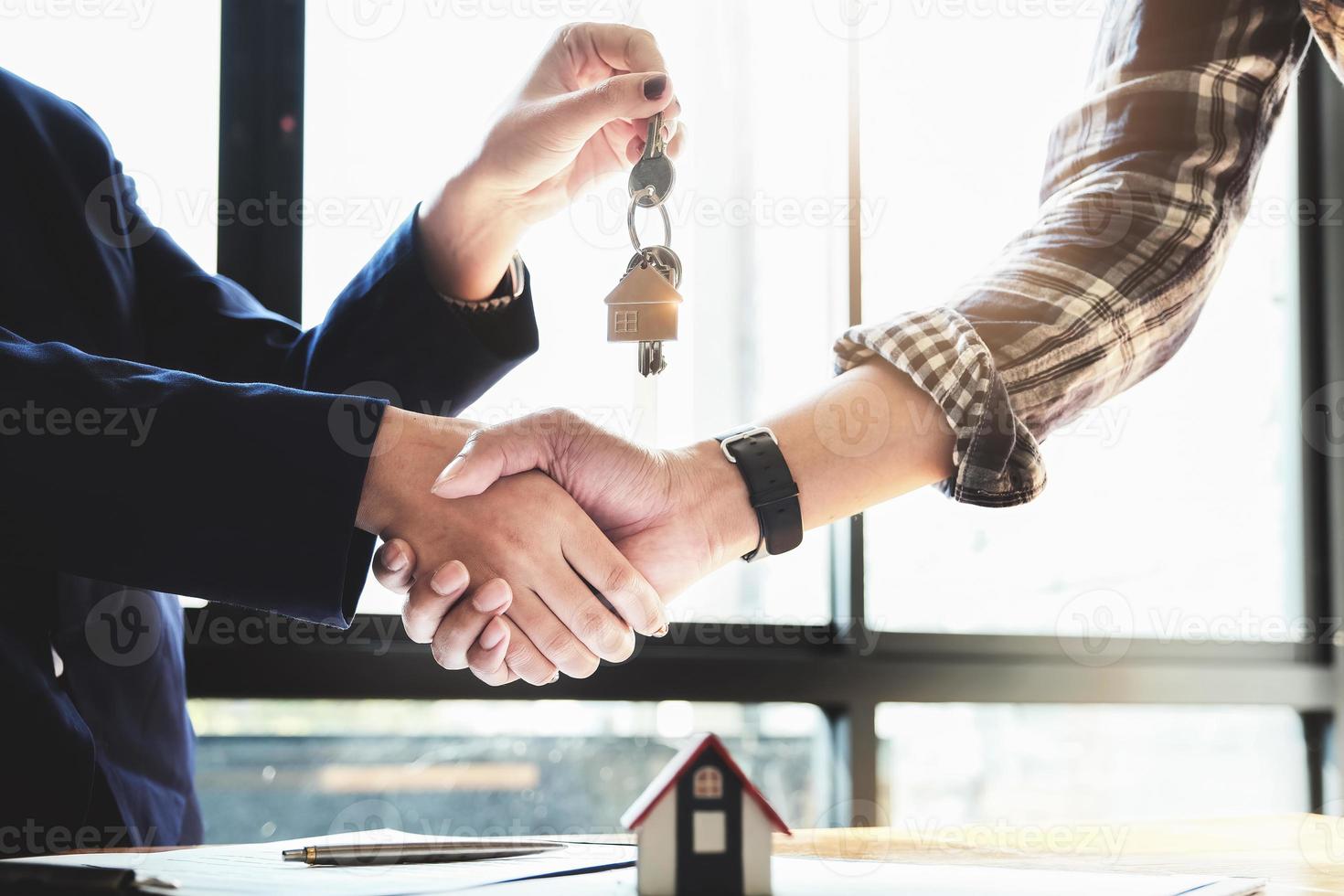 focus op de felicitatie handdruk. de makelaar stemt ermee in het huis te kopen en de sleutels aan de klant te overhandigen op het kantoor van de makelaar. conceptuele overeenkomst. foto