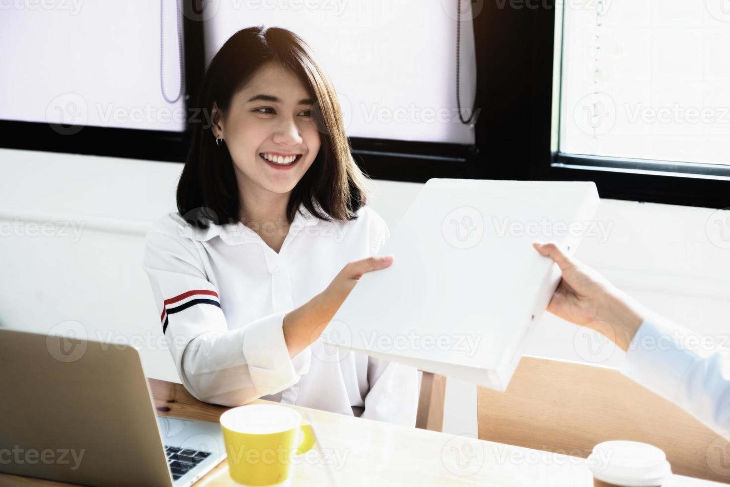 twee vrouwelijke bedrijfsmedewerkers glimlachten vrolijk naar elkaar terwijl ze elkaar mappen overhandigden. foto