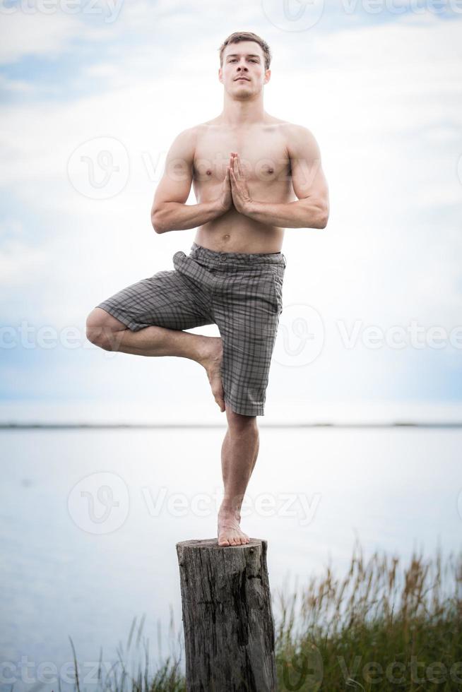 jonge volwassene die yoga doet op een boomstronk in de natuur foto