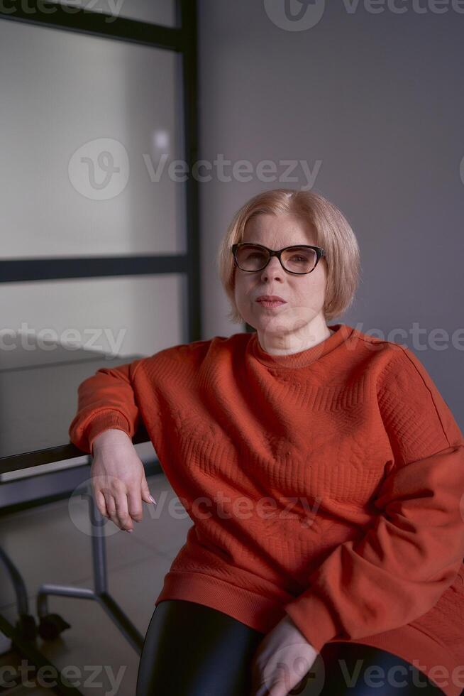 portret van een vrouw met een onbekwaamheid in een oranje trui en leer broek in de kantoor foto