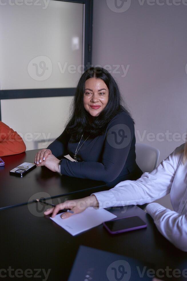 plus grootte vrouw in een zwart jurk Bij een vergadering in de kantoor foto