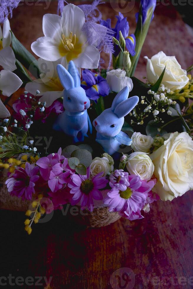 Pasen bloemen arrangement met twee blauw Pasen konijntjes in een rieten mand foto