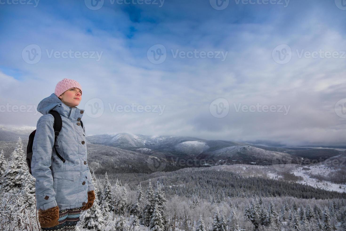 jonge vrouw die in de winter naar het uitzicht vanaf de top van een berg kijkt foto