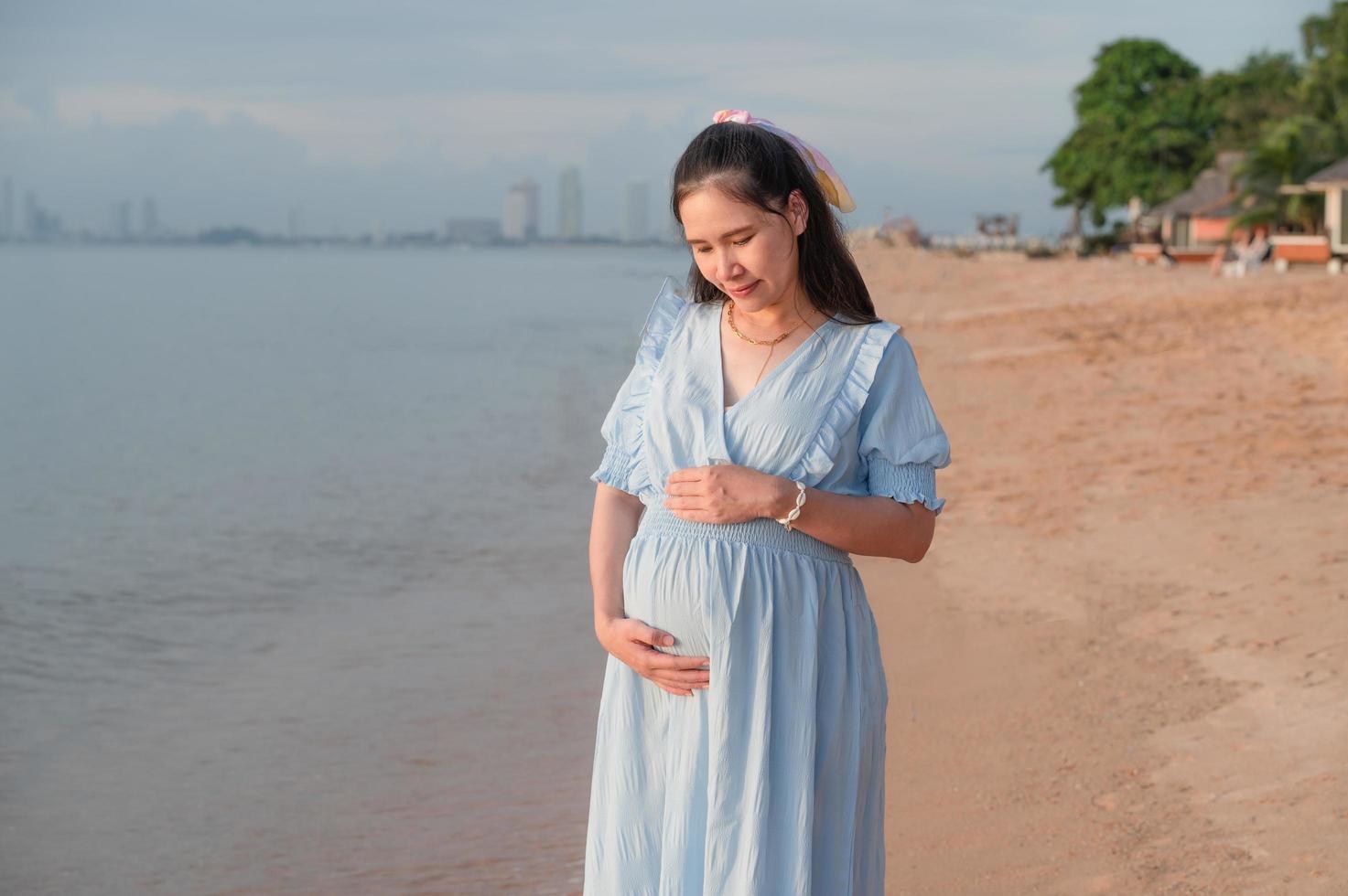 zwangere vrouw die gelukkig naar de zee reist foto