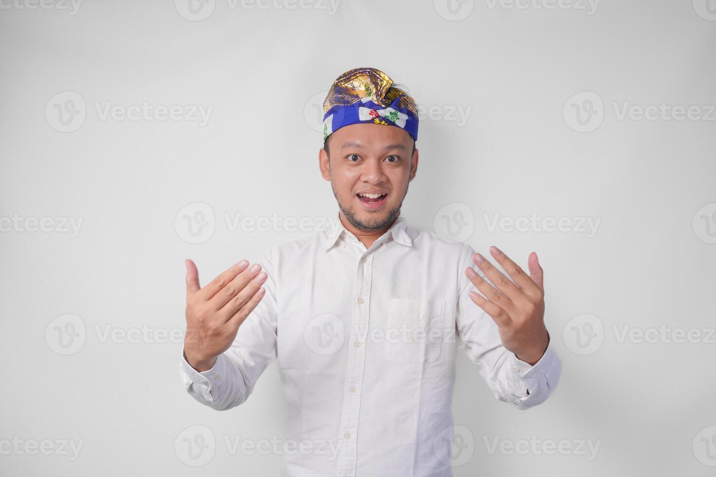 jong balinees knap Mens in traditioneel hoofdtooi uitnodigend naar komen met hand, gevoel gelukkig dat u kwam, geïsoleerd door wit achtergrond foto