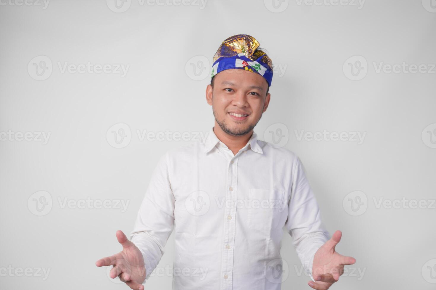 jong balinees knap Mens in traditioneel hoofdtooi uitnodigend naar komen met hand, gevoel gelukkig dat u kwam, geïsoleerd door wit achtergrond foto