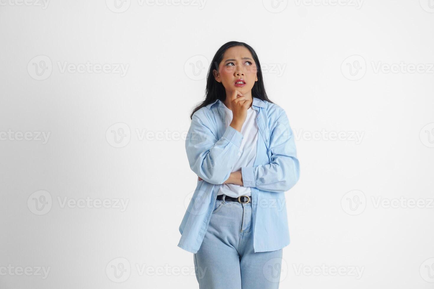 een attent Aziatisch vrouw vervelend blauw overhemd is verbeelden haar gedachten, geïsoleerd door wit achtergrond. foto