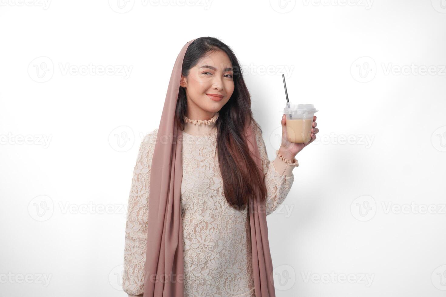 glimlachen Aziatisch moslim vrouw in hoofddoek sluier hijab Holding koffie in een plastic kop aan het wachten voor iftar naar drankje. Ramadan concept foto