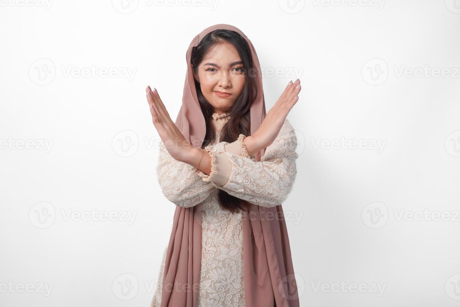 jong Aziatisch moslim vrouw vervelend sluier hijab gebaren een Nee afwijzing, weigeren gebruik makend van handen en vingers, geïsoleerd door wit achtergrond. Ramadan en eid mubarak concept foto