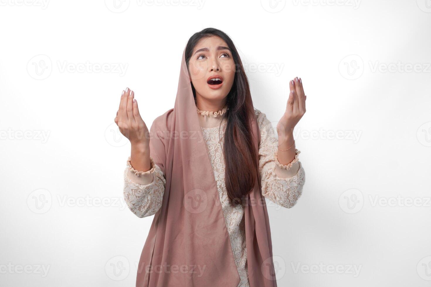 religieus Aziatisch moslim vrouw vervelend sluier hoofddoek met handen in bidden gebaar naar god, staand over- geïsoleerd wit achtergrond. Ramadan en eid al fitr concept foto