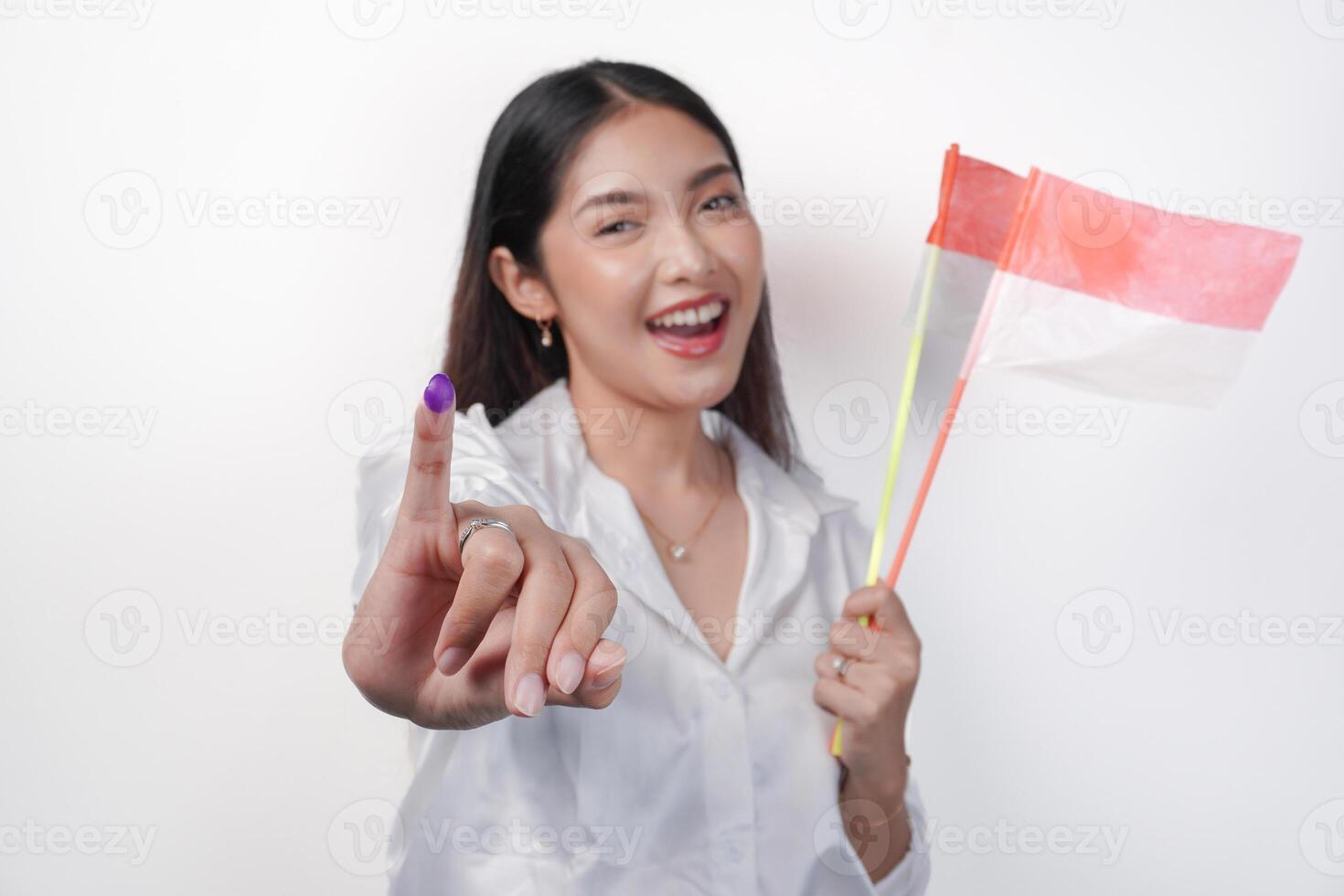 portret van gelukkig Aziatisch vrouw trots tonen weinig vinger gedoopt in Purper inkt na stemmen voor president en parlement verkiezing, links hand- Holding Indonesië mini vlaggen. onafhankelijkheid dag concept. foto