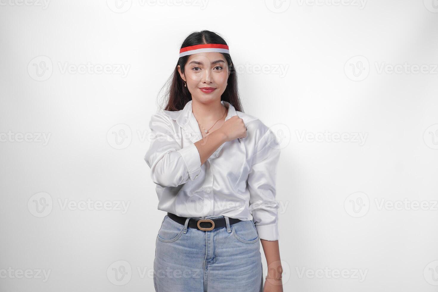 mooi Aziatisch vrouw vervelend vlag hoofdband met vuist Aan borst vieren Indonesië onafhankelijkheid dag, staand over- geïsoleerd wit achtergrond. onafhankelijkheid dag advertentie concept foto