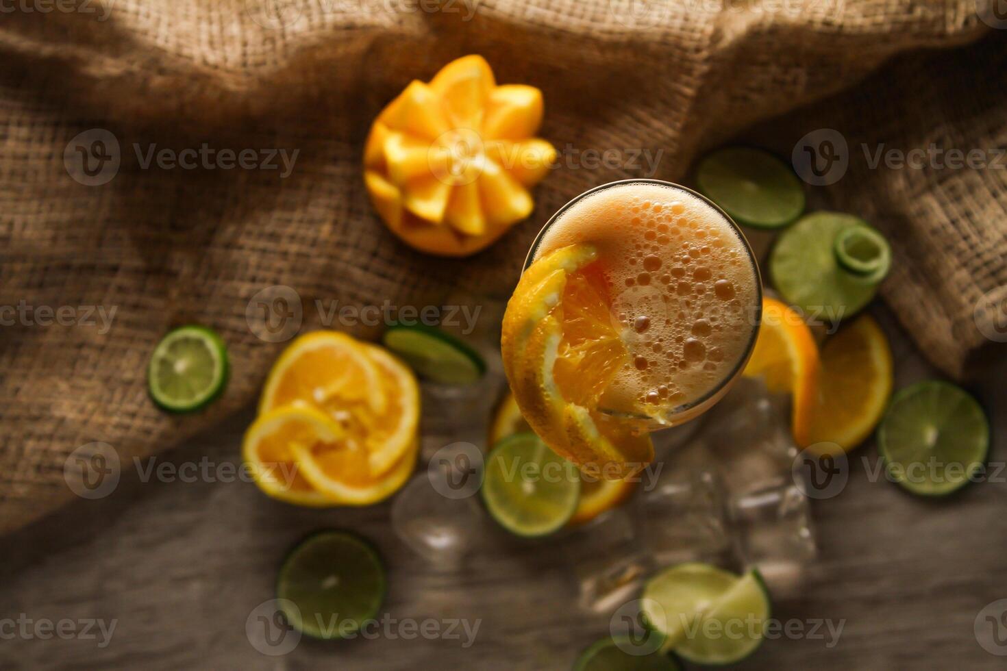 vers oranje sap met citroen en ijs kubus geserveerd in beschikbaar glas geïsoleerd Aan tafel top visie van gezond ochtend- sap drinken foto