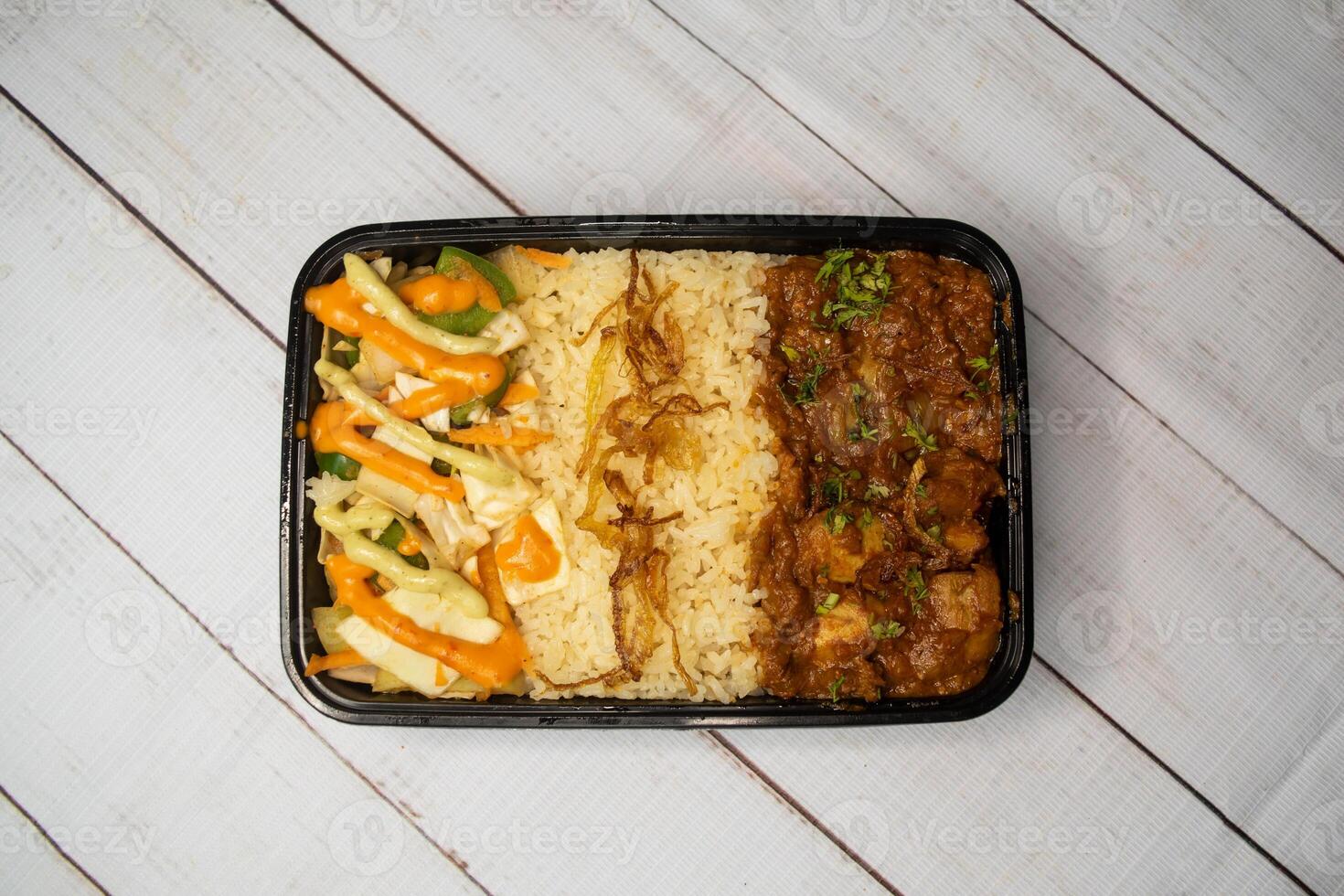 kip bhuna met Pulao biryani rijst- met komkommer, dip saus en citroen plak geserveerd in schotel geïsoleerd Aan houten tafel top visie van bangladesh en Indisch pittig lunch voedsel foto