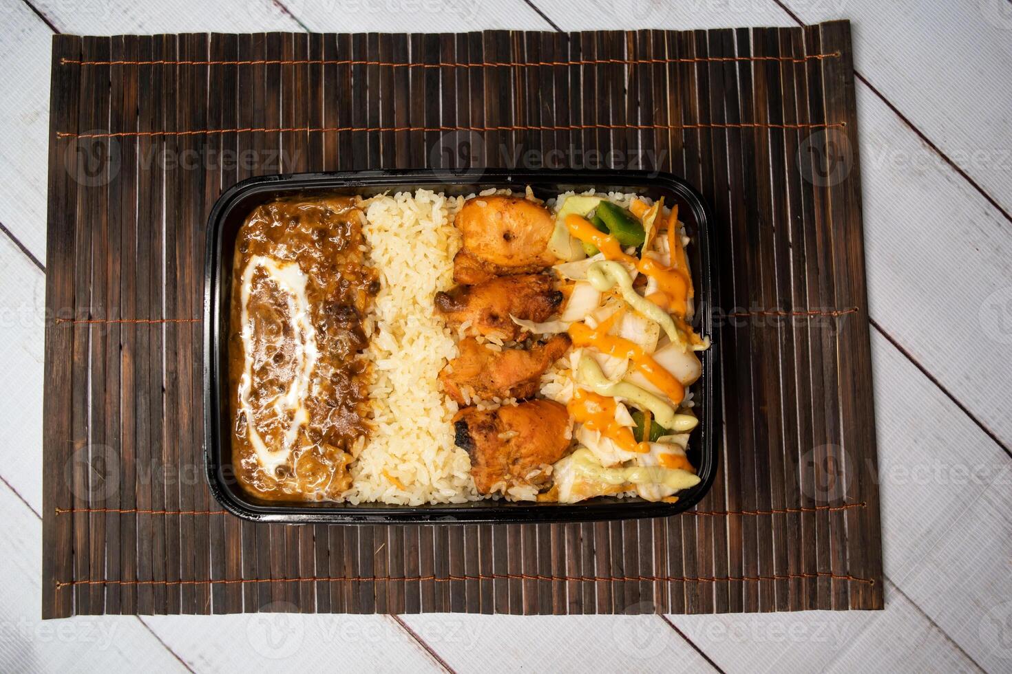 kip tikka en Pulao met dal makhani biryani rijst- met komkommer, dip saus en citroen plak geserveerd in schotel geïsoleerd Aan houten tafel top visie detailopname van bangladesh en Indisch pittig lunch voedsel foto