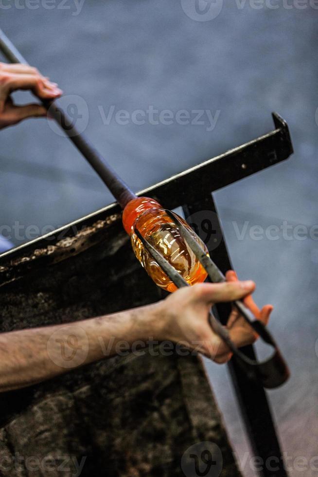 man handen close-up werken aan een stuk geblazen glas foto