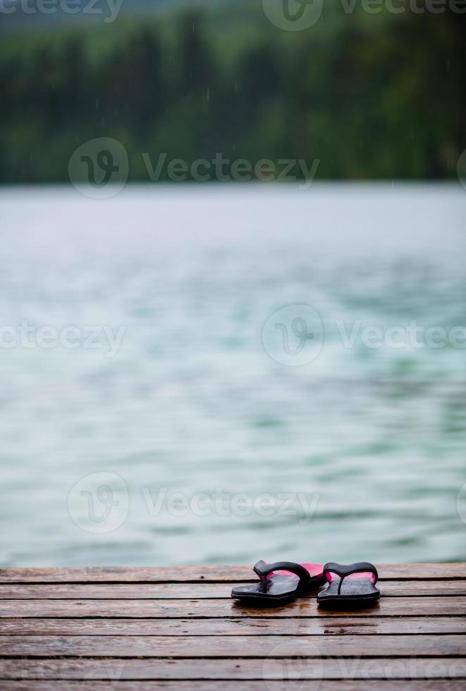 teenslippers op een dok voor een turquoise watermeer foto