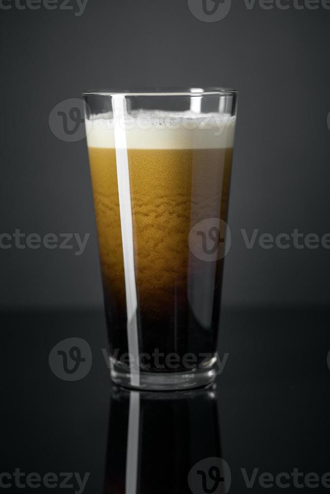 tap stikstof verse en romige zwarte stout bier pint op zwarte achtergrond foto