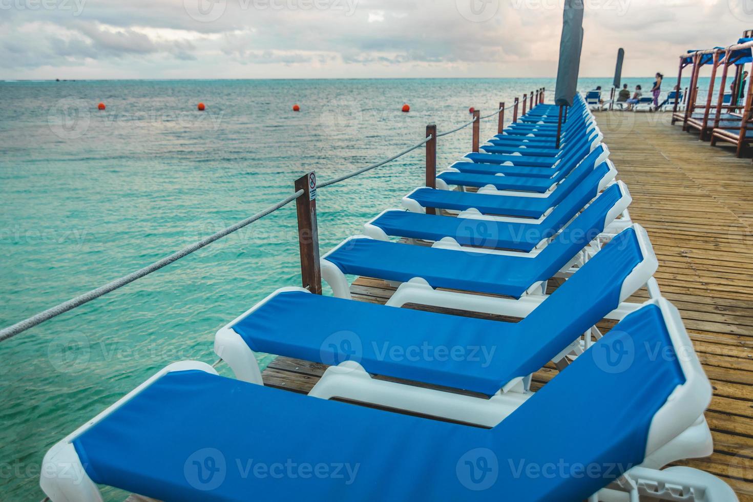 houten pier en lange blauwe stoelen met niemand foto