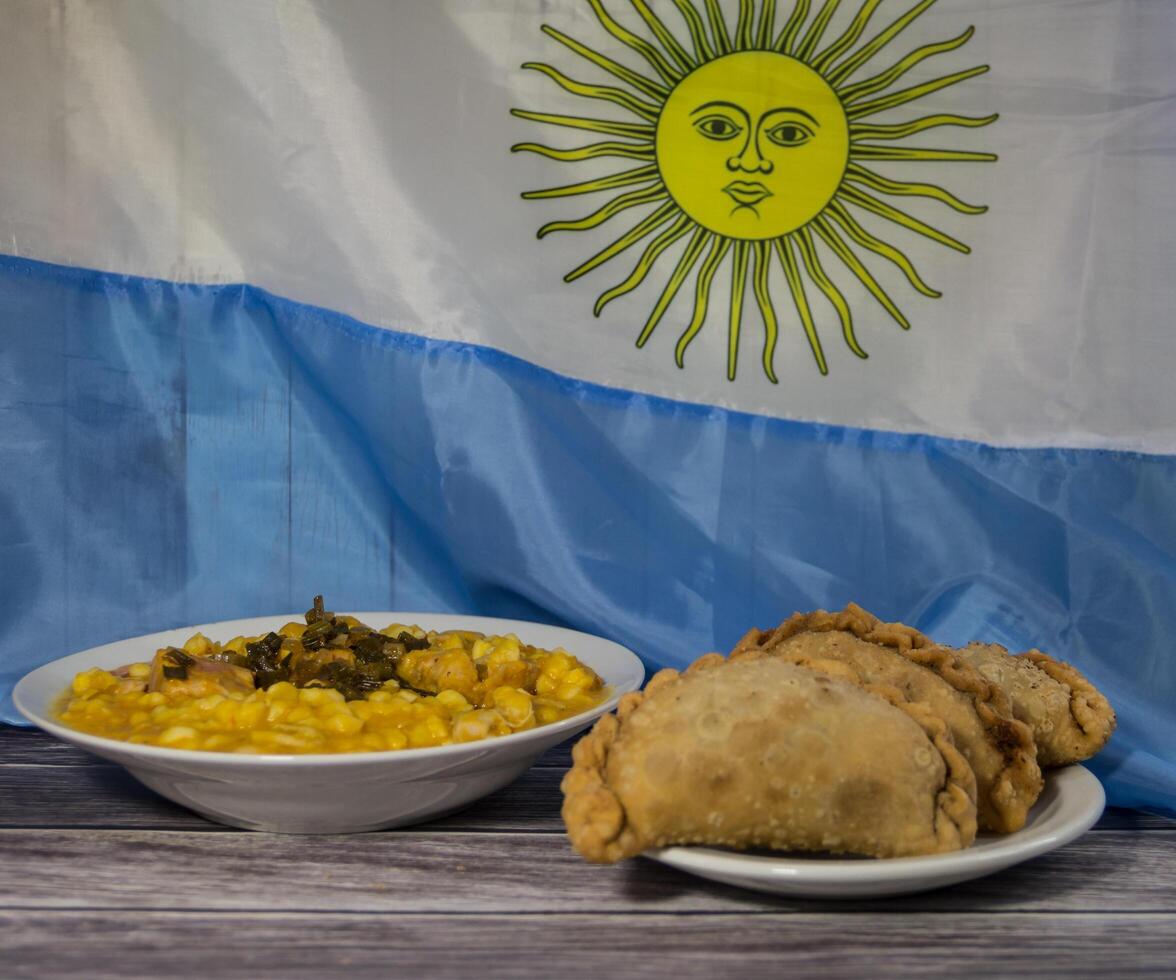 bord van locro en empanadas met de Argentijns vlag, traditioneel patriottisch voedsel foto