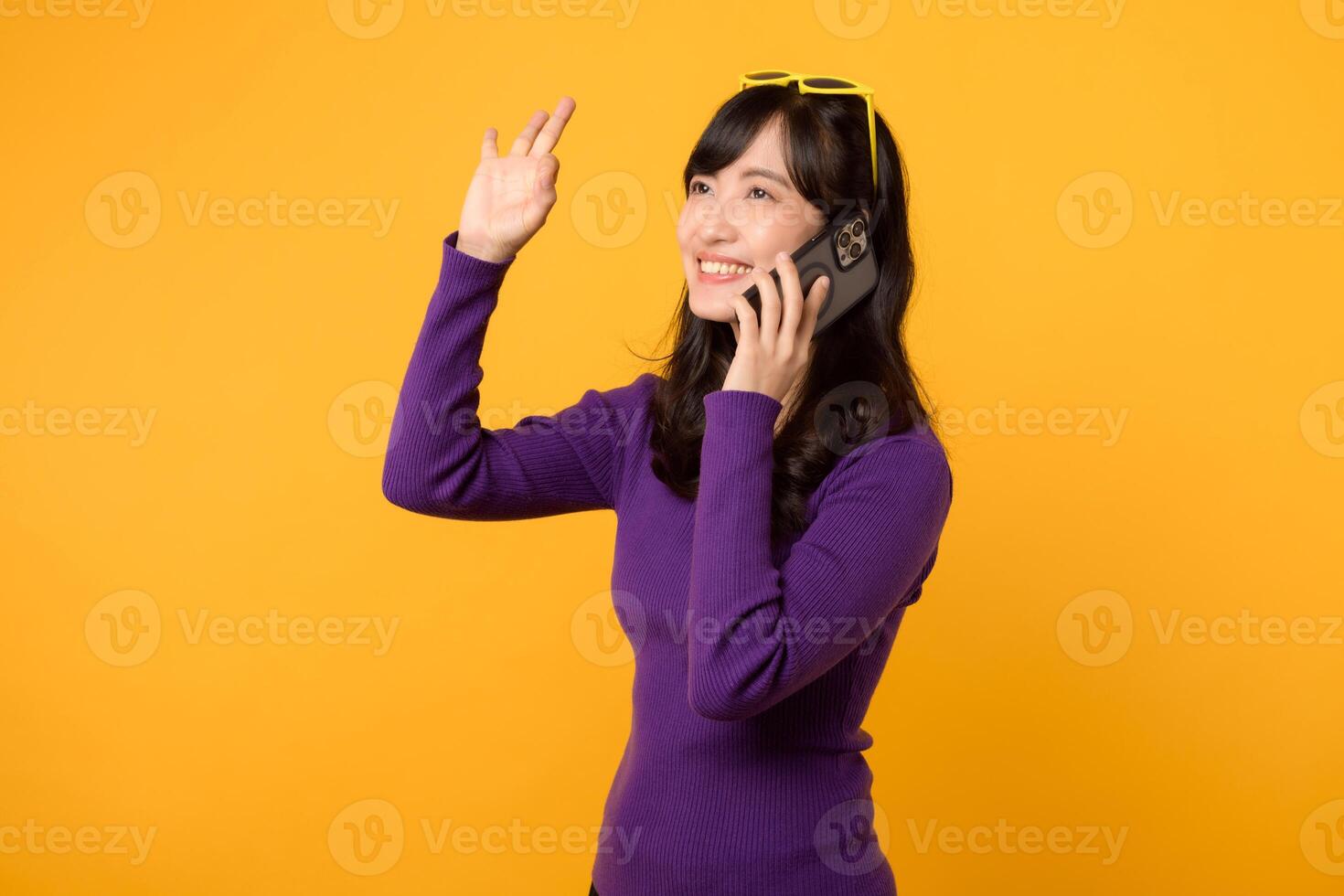 verspreiding geluk met een jong Aziatisch vrouw jaren '30, aandoen een Purper shirt, tonen Oke hand- teken terwijl gebruik makend van smartphone Aan geel achtergrond. foto