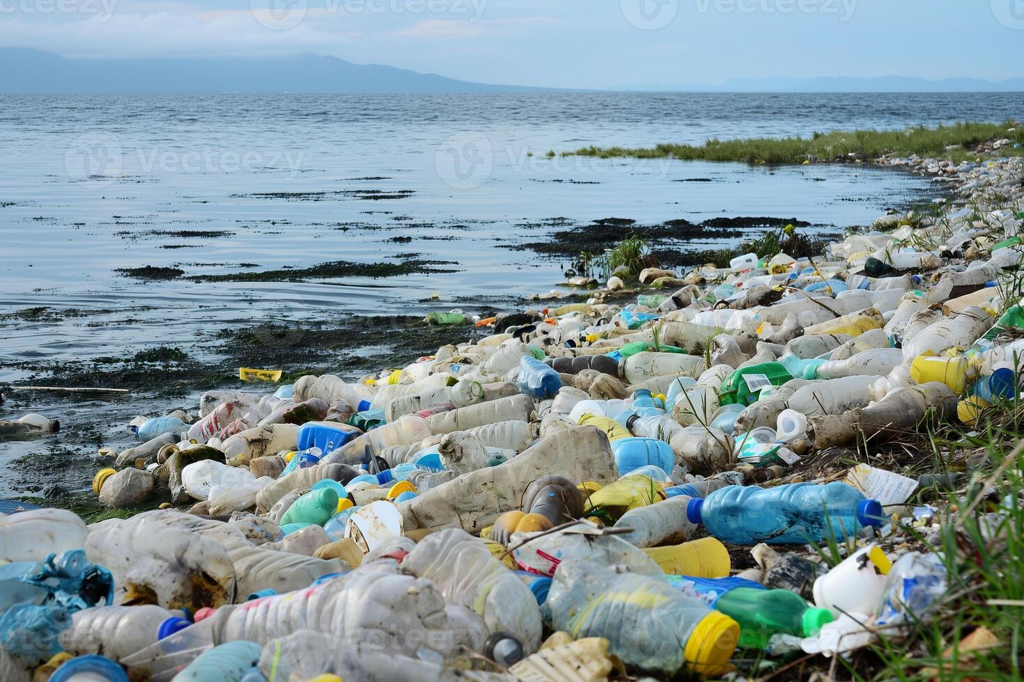 een strand bezaaid met plastic afval, vervuilend de oceaan en schade toebrengen marinier leven. foto