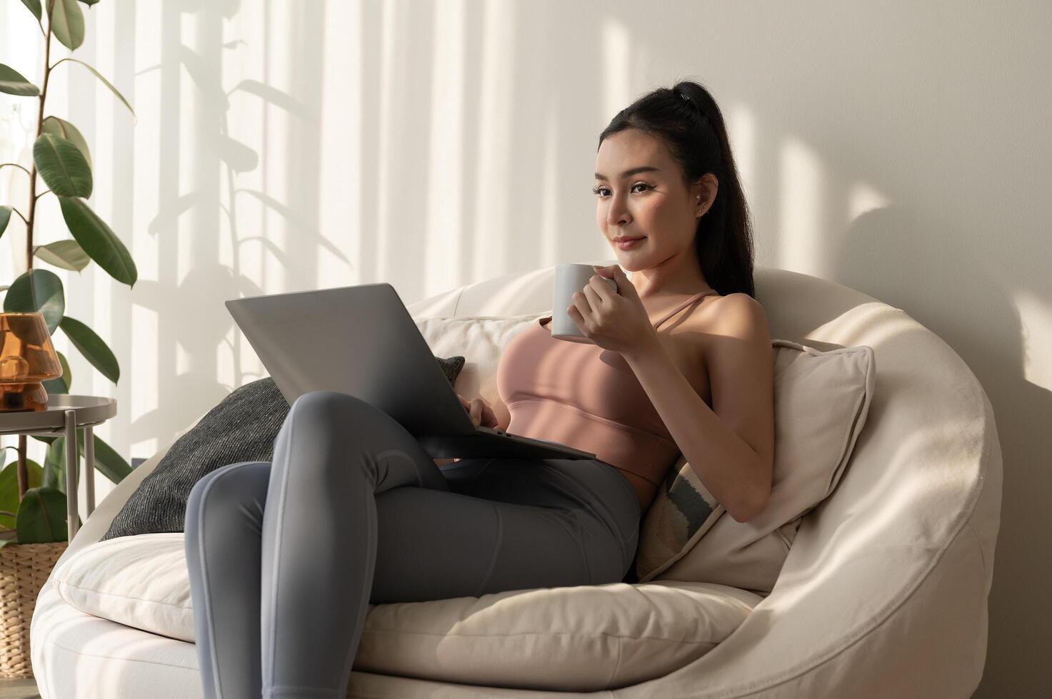 jong Aziatisch vrouw werken met laptop in leven kamer Bij huis foto