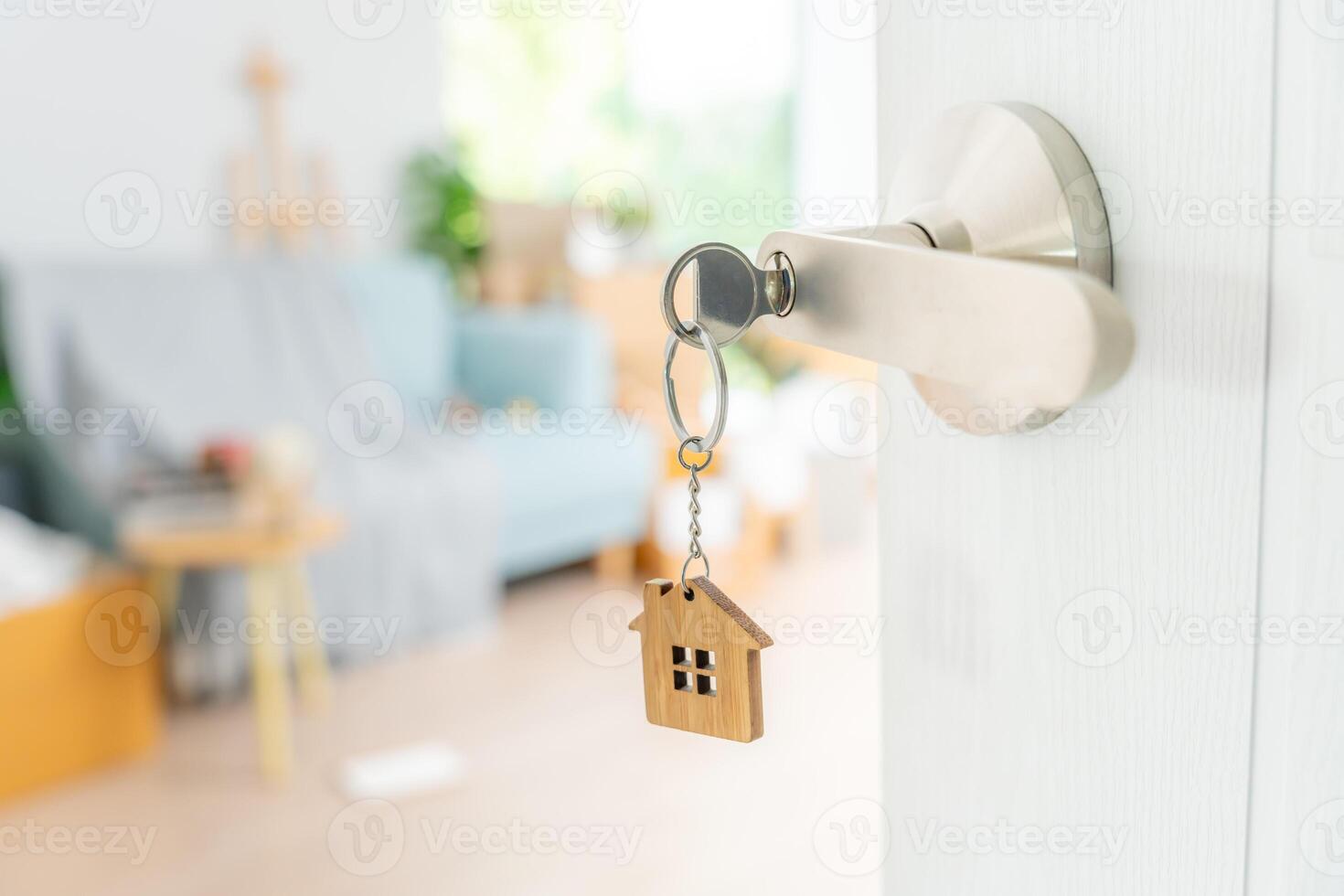 in beweging huis, verhuizing. de sleutel was ingevoegd in de deur van de nieuw huis, binnen de kamer was een karton doos met persoonlijk bezittingen en meubilair. Actie in de appartement of condominium foto