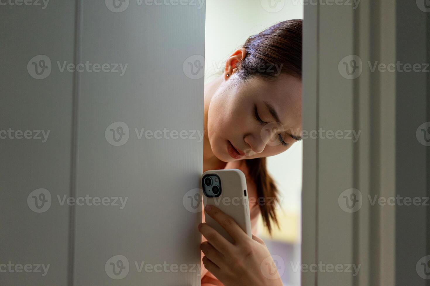 de Aziatisch meisje verborg achter de deur in angst foto