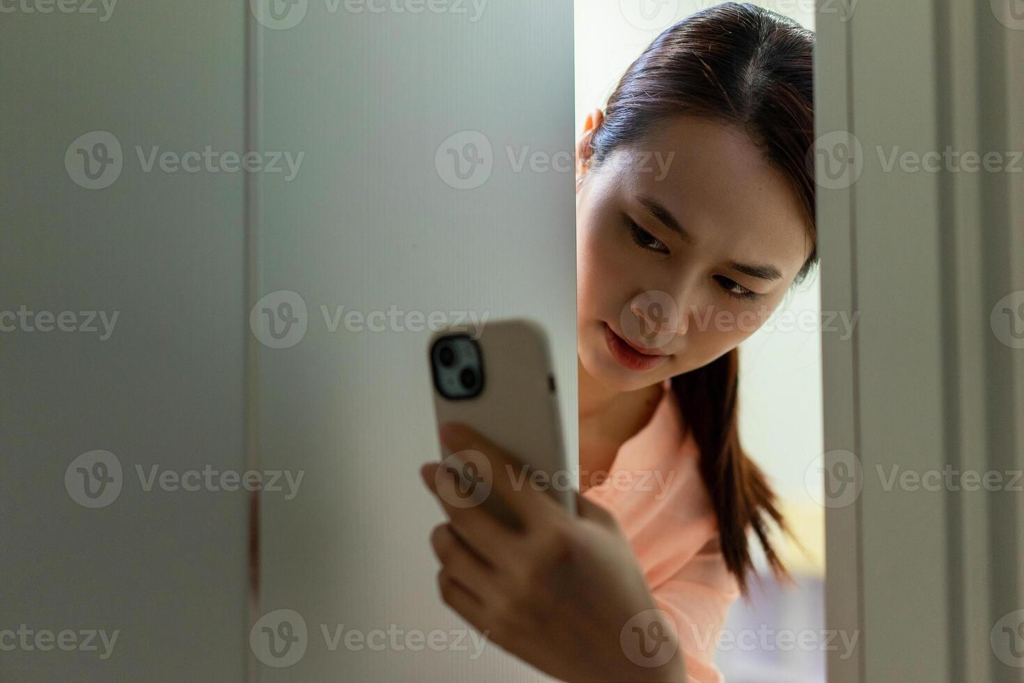 de Aziatisch meisje verborg achter de deur in angst foto