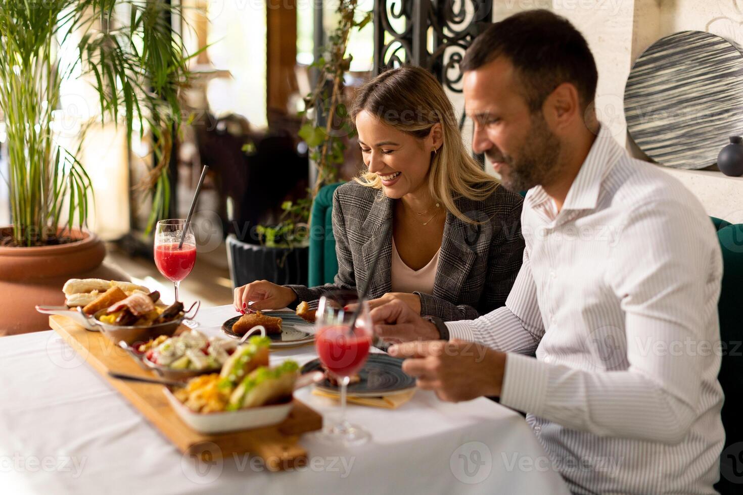 jong paar hebben lunch en drinken vers geperst sap in de restaurant foto