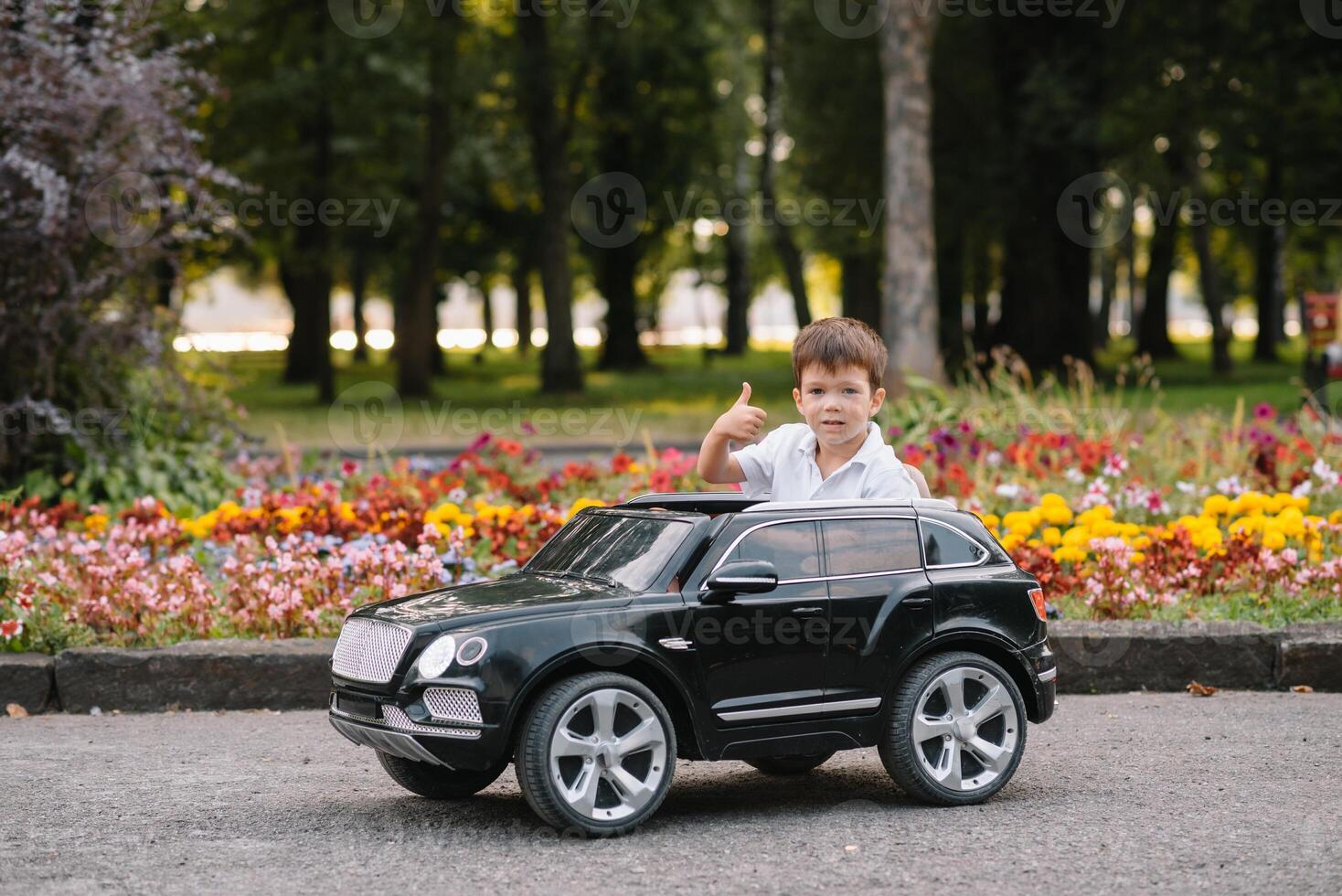 schattig jongen in rijden een zwart elektrisch auto in de park. grappig jongen ritten Aan een speelgoed- elektrisch auto. kopiëren ruimte. foto